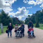 Six people from KCIL standing for a photo on one of the Kew paths, two people are in wheelchairs