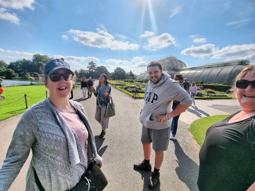KCIL members enjoy the sun at Kew Gardens, with the Palm House in the background, to the right