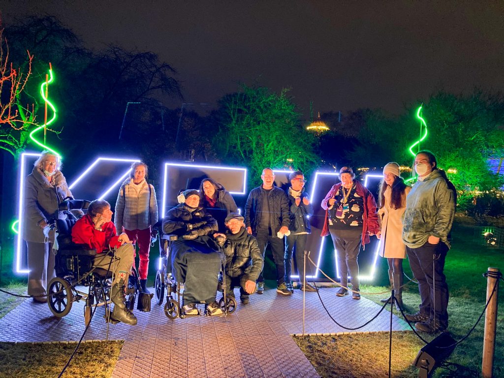 Photo of the KCIL group in front of a lighted sign that says Kew