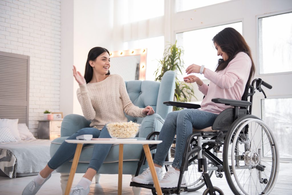 A woman in a wheelchair laughing with a woman sitting on a chair