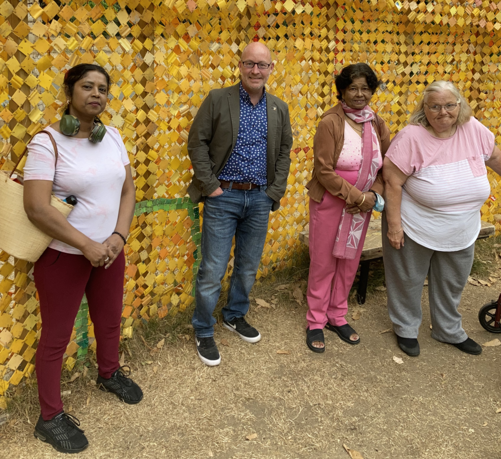 KCIL staff and members in fron of a gold, sparkly wall at Kew Gardens