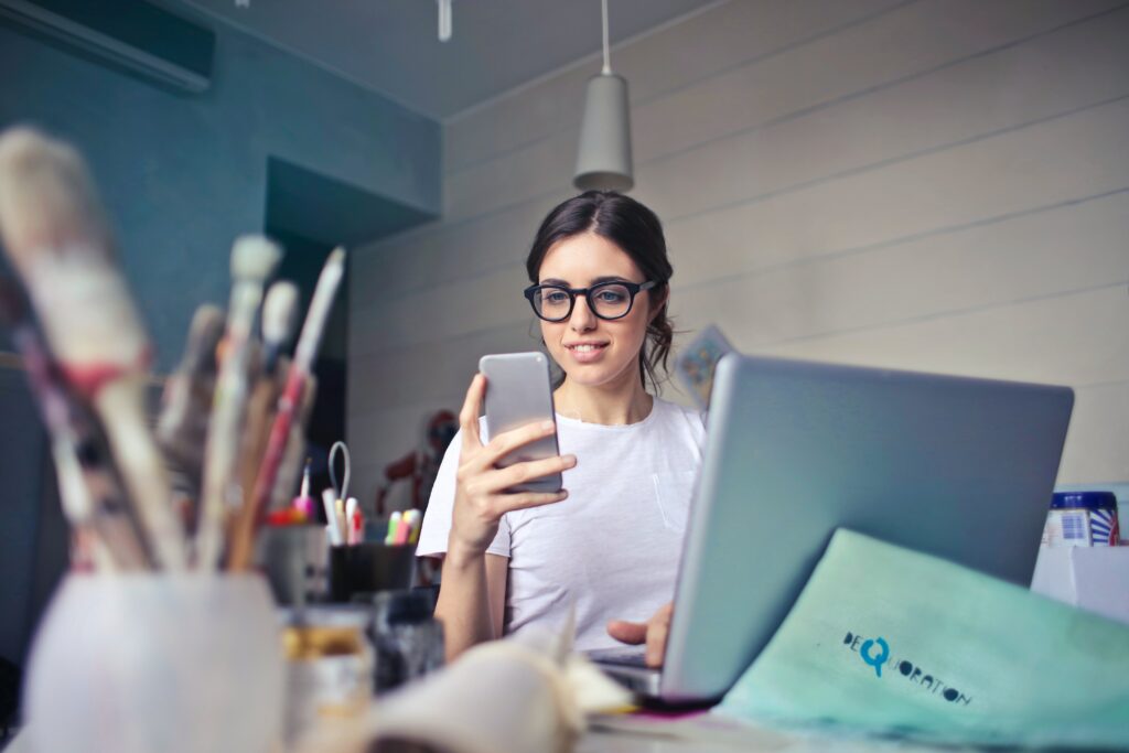 A woman in front of her laptop on her phone