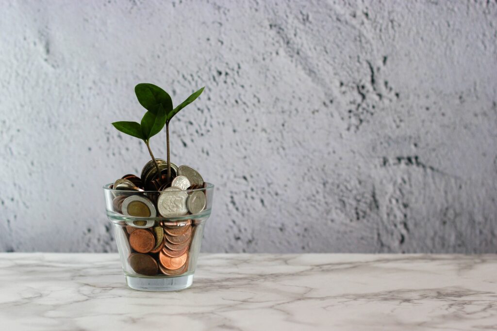 A plant growing out of a glass full of coins