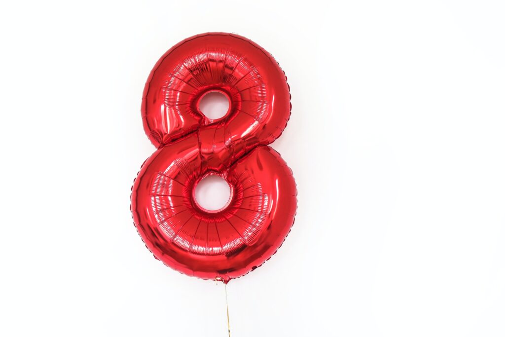 A large, shiny red balloon in the shape of a number 8