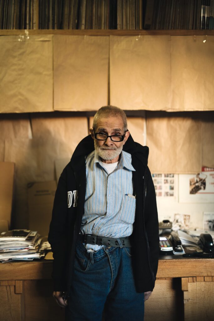 An older man stands at a workbench