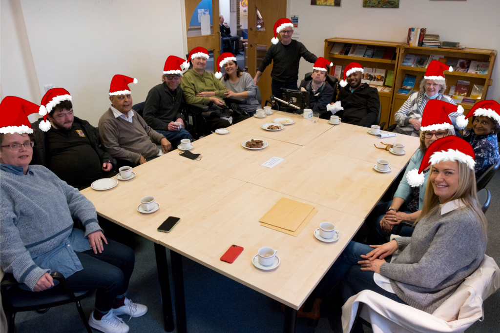 An image of people sad around a table with edited on Santa hats.