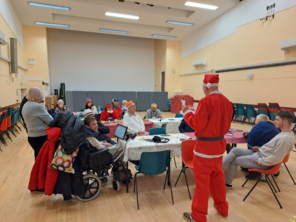 An image of KCIL members sat around tables eating food and taking part in a quiz.