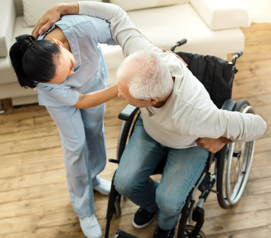 A woman helps a man to sit in a wheelchair