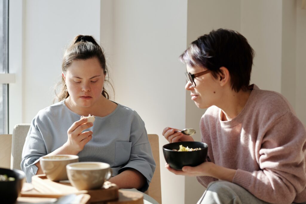 Two women, one with Down's Syndrome, eating from bowls