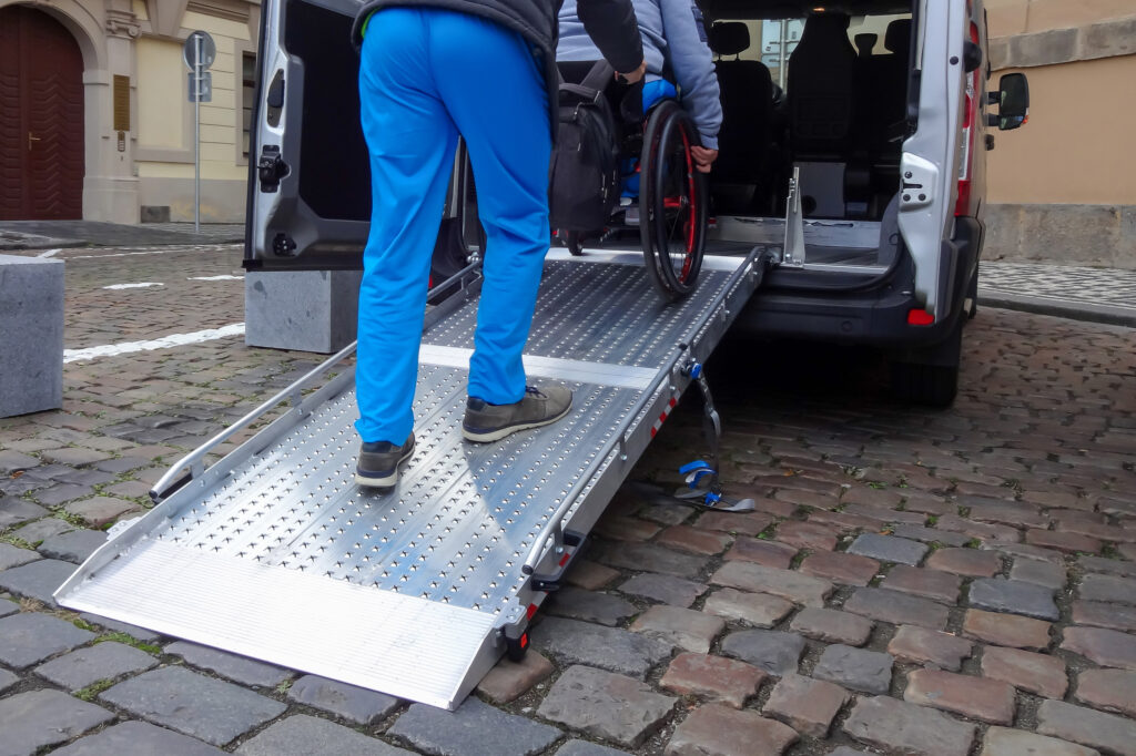 A photo showing the back ramp of a wheelchair accessible vehicle, with someone pushing a wheelchair