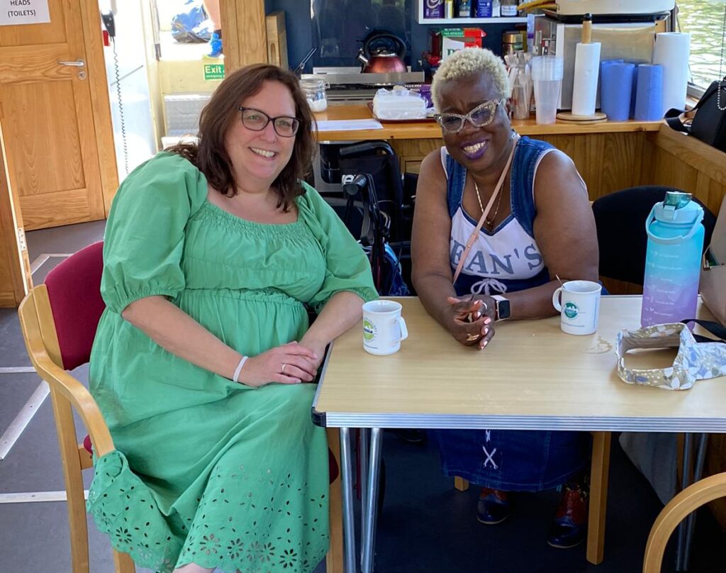 KCIL team member Helen with a KCIL member inside the boat having a cup of tea