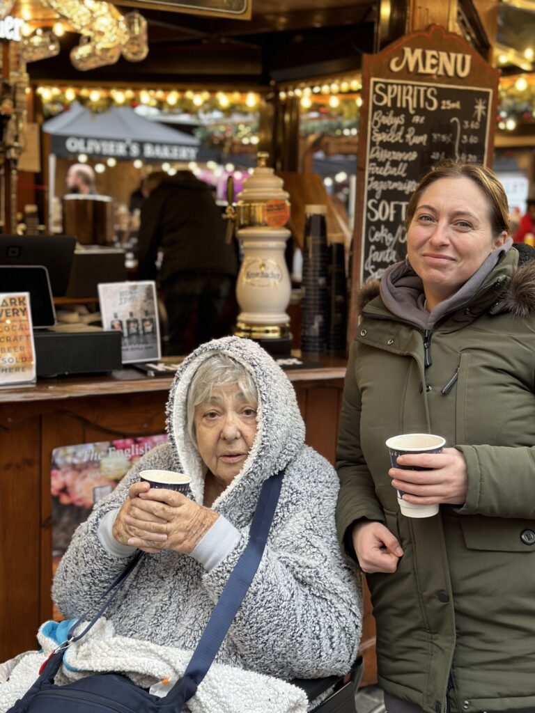 KCIL member with her PA enjoying hot chocolate in the marketplace