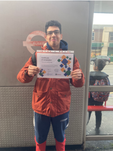 Our first student with his completion certificate by a bus stop