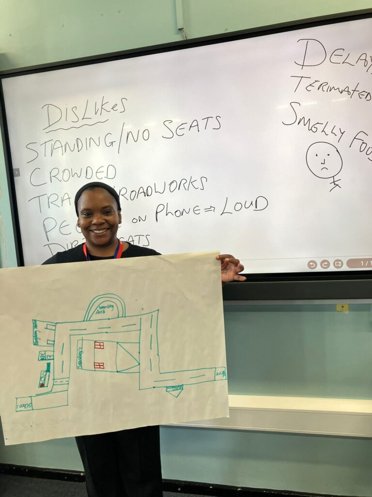 Natalina in front of a white board holding up one of the maps drawn by a student