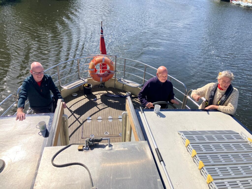 A KCIL service user drives the boat next to KCIL CEO Jason